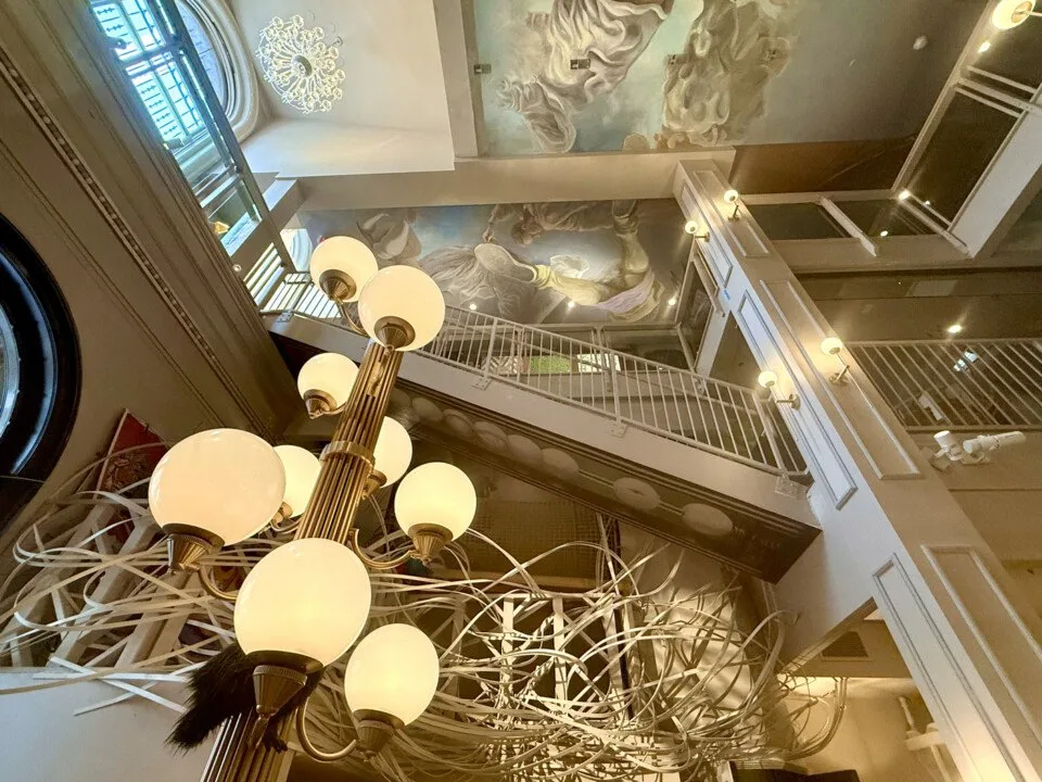 Six-story atrium of the former Manufacturer's National Bank with ceiling murals and chandelier at Ministry of Awe