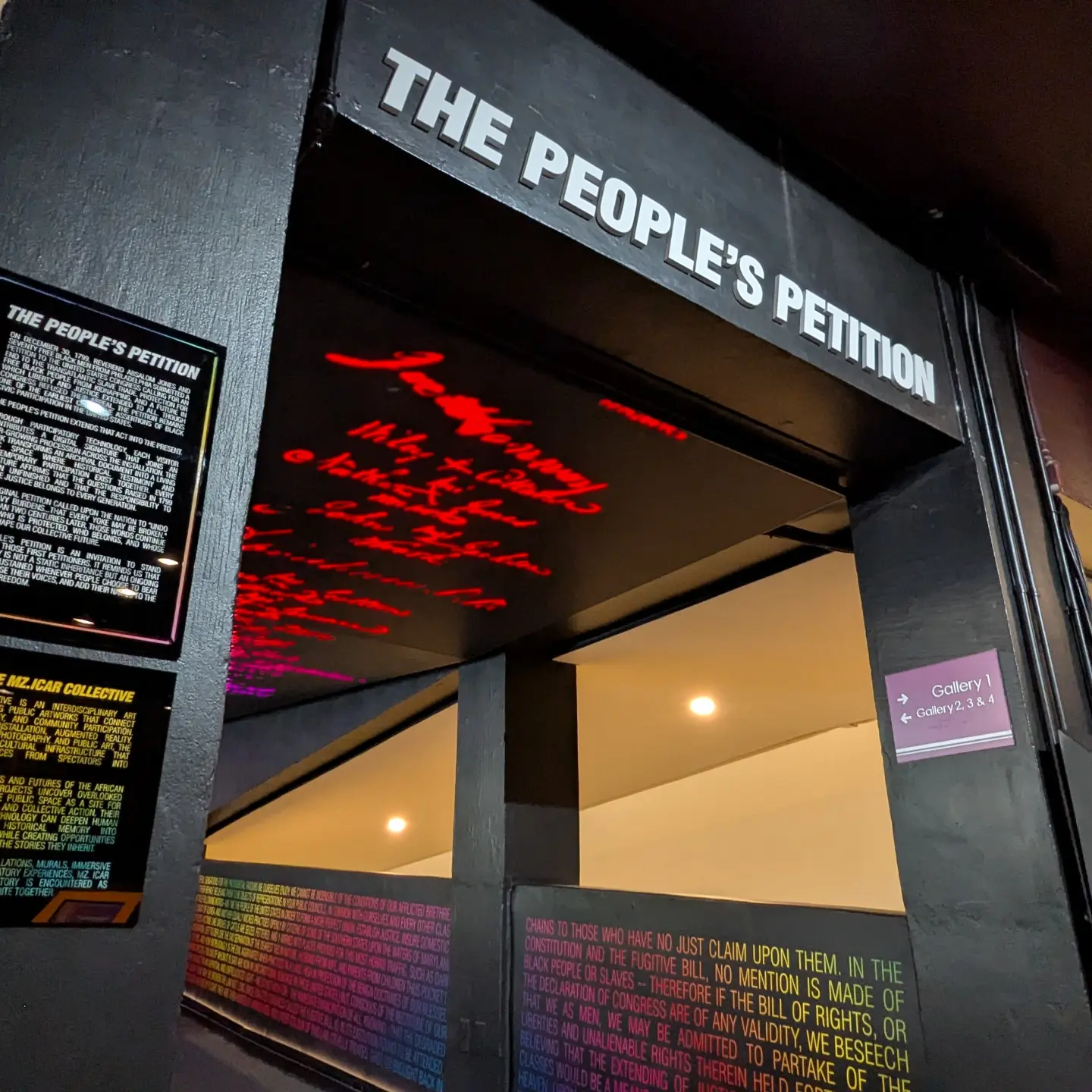 Hallway entrance to the interactive museum installation with visitor signatures glowing red on the LED video wall overhead